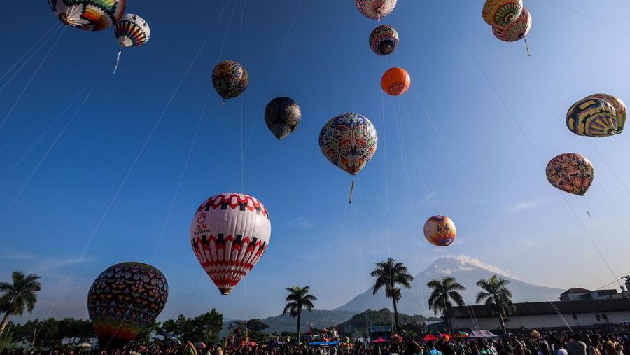 WONOSOBO, INDONESIA - APRIL 23: Hot air balloons fly over the sky during a balloon festival on the Eid al-Fitr holiday at Ronggolawe Stadion on April 23, 2023, in Wonosobo, Central Java, Indonesia. Javanese people fly giant hot air balloons during Eid, which has long been a tradition of the Wonosobo regency. (Photo by Garry Lotulung/Anadolu Agency via Getty Images)