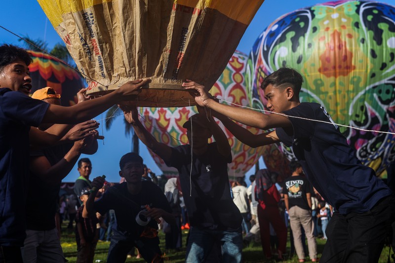 1252105442 WONOSOBO, INDONESIA - APRIL 23: Hot air balloons fly over the sky during a balloon festival on the Eid al-Fitr holiday at Ronggolawe Stadion on April 23, 2023, in Wonosobo, Central Java, Indonesia. Javanese people fly giant hot air balloons during Eid, which has long been a tradition of the Wonosobo regency. (Photo by Garry Lotulung/Anadolu Agency via Getty Images)