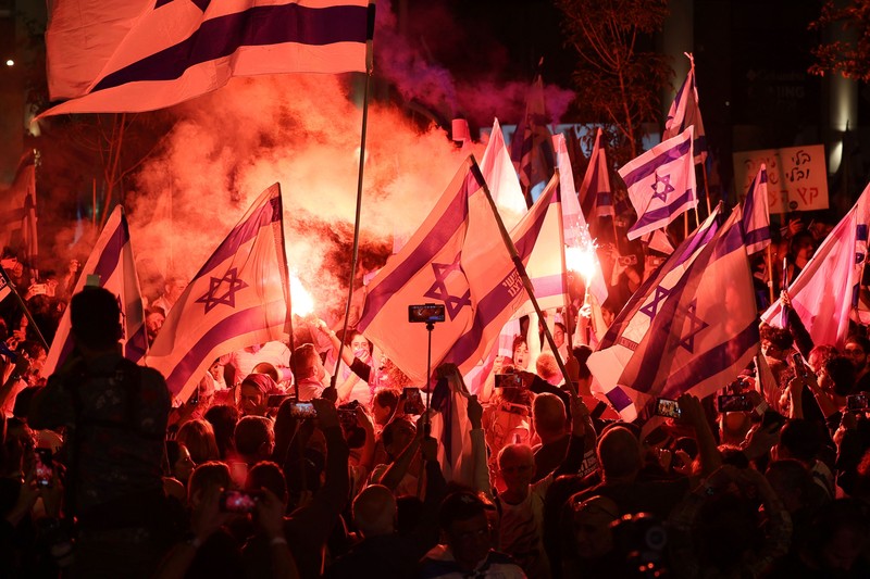 Demonstran menyalakan suar selama unjuk rasa di Tel Aviv untuk memprotes RUU perbaikan peradilan pemerintah Israel, saat negara itu memulai perayaan ulang tahun ke-75, pada 25 April 2023. (JACK GUEZ/AFP via Getty Images)