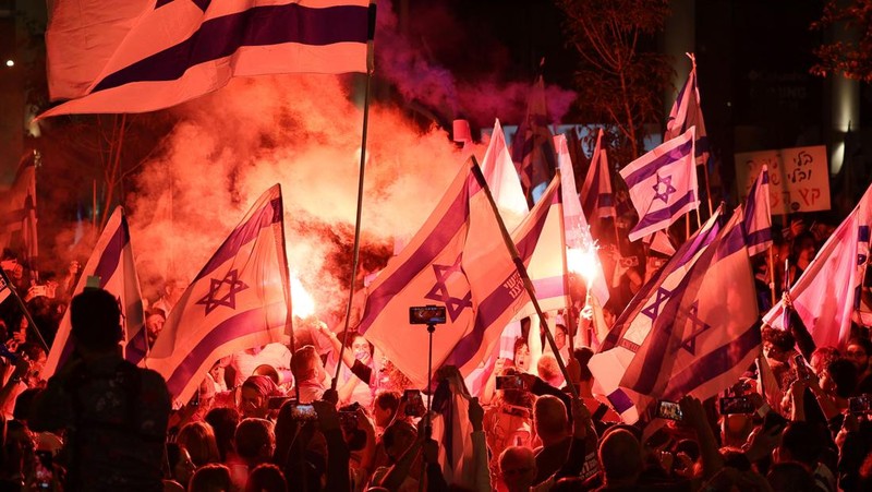 Demonstran menyalakan suar selama unjuk rasa di Tel Aviv untuk memprotes RUU perbaikan peradilan pemerintah Israel, saat negara itu memulai perayaan ulang tahun ke-75, pada 25 April 2023. (JACK GUEZ/AFP via Getty Images)