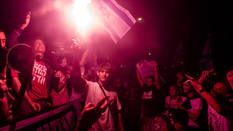 Demonstran menyalakan suar selama unjuk rasa di Tel Aviv untuk memprotes RUU perbaikan peradilan pemerintah Israel, saat negara itu memulai perayaan ulang tahun ke-75, pada 25 April 2023. (JACK GUEZ/AFP via Getty Images)