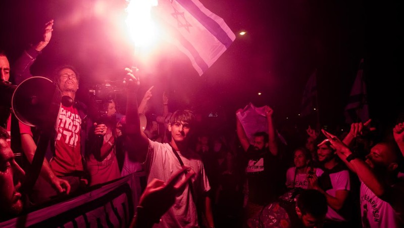 Demonstran menyalakan suar selama unjuk rasa di Tel Aviv untuk memprotes RUU perbaikan peradilan pemerintah Israel, saat negara itu memulai perayaan ulang tahun ke-75, pada 25 April 2023. (JACK GUEZ/AFP via Getty Images)