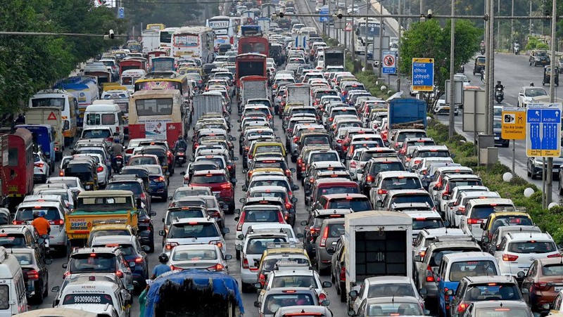 Orang-orang mengunjungi Gerbang India di New Delhi. - Setiap pagi dan sore dan selama beberapa jam di antara puluhan juta orang India duduk menganggur di jalan raya yang macet dan bergelantungan di sisi kereta penumpang yang padat di tempat yang menjadi negara terpadat di dunia. (Sajjad HUSSAIN / AFP)