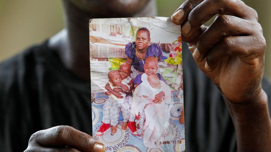 Steven Mwiti holds a photograph of his late wife Joan Bahati, a follower of a Christian cult named