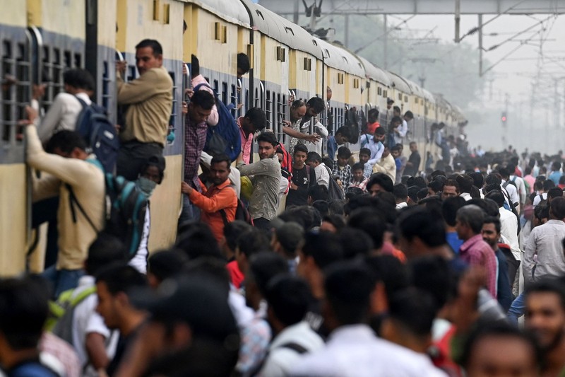 Orang-orang mengunjungi Gerbang India di New Delhi. - Setiap pagi dan sore dan selama beberapa jam di antara puluhan juta orang India duduk menganggur di jalan raya yang macet dan bergelantungan di sisi kereta penumpang yang padat di tempat yang menjadi negara terpadat di dunia. (Sajjad HUSSAIN / AFP)