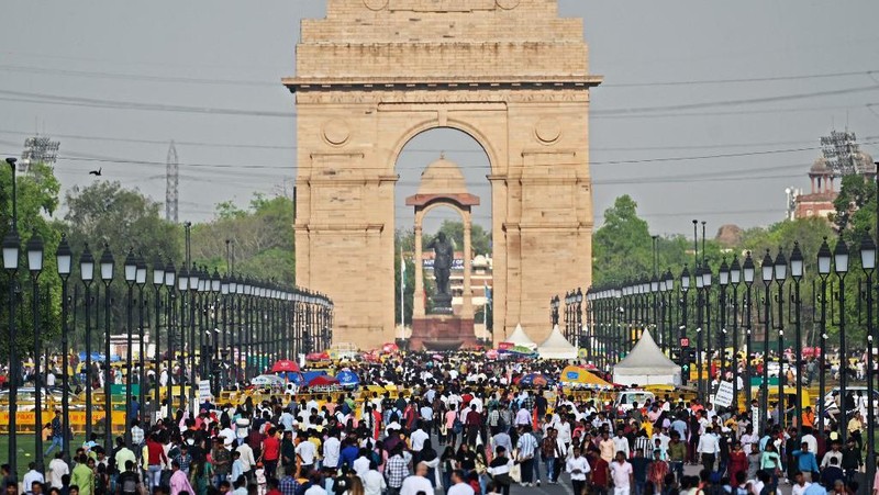 Orang-orang mengunjungi Gerbang India di New Delhi. - Setiap pagi dan sore dan selama beberapa jam di antara puluhan juta orang India duduk menganggur di jalan raya yang macet dan bergelantungan di sisi kereta penumpang yang padat di tempat yang menjadi negara terpadat di dunia. (Sajjad HUSSAIN / AFP)