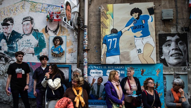 Bendera, spanduk, dan pita dipajang di jalan-jalan untuk merayakan kemenangan gelar Serie A ketiga pada 27 April 2023 di Naples, Italia. Kota Naples sedang bersiap untuk merayakan kemenangan Scudetto ketiga di kejuaraan Serie A. Di jalan-jalan pusat bersejarah dan di berbagai distrik Napoli, dekorasi, bendera, dan spanduk telah dipasang untuk merayakan kejuaraan sepak bola yang dimainkan oleh tim yang dilatih oleh Spalletti. Para pemain bisa menjadi juara Italia lebih awal, jika mereka berhasil mengalahkan Salernitana dalam derby Campania dalam pertandingan yang akan dimainkan pada hari Minggu pukul 15:00 di Stadion Diego Armando Maradona dan jika Lazio gagal menang tandang melawan Internazionale. Napoli telah memenangkan dua Scudetti dalam sejarahnya pada musim 1986-1987 dan 1989-1990, kedua kemenangan tersebut diperoleh dengan kehadiran Diego Armando Maradona, para fans Neapolitan menunggu untuk dapat merayakan 33 tahun setelah kesuksesan terakhir. (Ivan Romano/Getty Images)