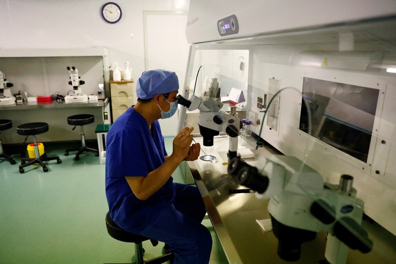 Anggota staf berjalan melewati ruang tunggu pusat reproduksi berbantuan di Rumah Sakit Keluarga Sempurna Beijing, yang berspesialisasi dalam perawatan kesuburan, di Beijing, China 6 April 2023. (REUTERS/Tingshu Wang)