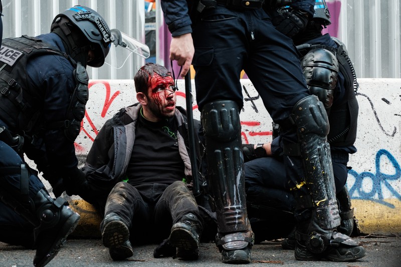 French Republican Security Corps (CRS - Compagnies Republicaines de Securite) police officers and Police officers take position next to a burning bicycle-sharing station during a demonstration on May Day (Labour Day), to mark the international day of the workers, more than a month after the government pushed an unpopular pensions reform act through parliament, in Paris, on May 1, 2023. - Opposition parties and trade unions have urged protesters to maintain their three-month campaign against the law that will hike the retirement age to 64 from 62. (Photo by Geoffroy Van der Hasselt / AFP)