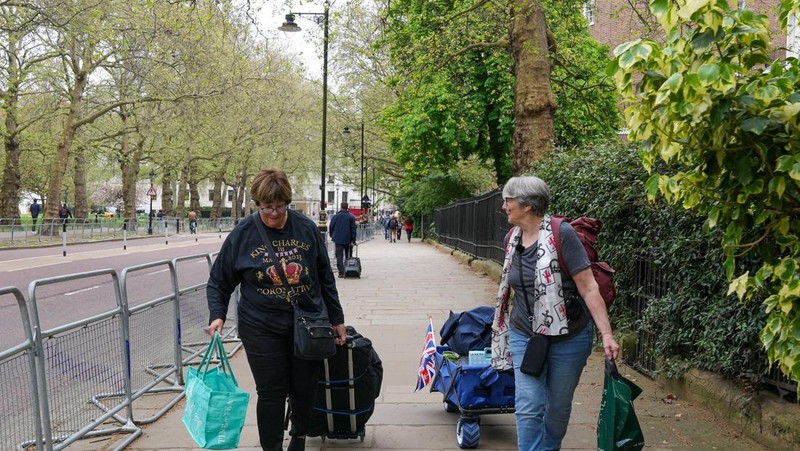 Penggemar kerajaan Inggris, Mary-Jane Willows dari Inggris dan Donna Werner dari AS berjalan ke The Mall untuk mendirikan kemah jelang Penobatan Raja Charles, di London, Inggris, Selasa (2/5/2023). REUTERS/Maja Smiejkowska