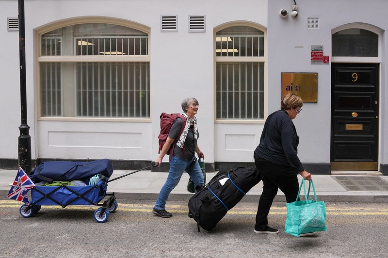 Penggemar kerajaan Inggris, Mary-Jane Willows dari Inggris dan Donna Werner dari AS berjalan ke The Mall untuk mendirikan kemah jelang Penobatan Raja Charles, di London, Inggris, Selasa (2/5/2023). REUTERS/Maja Smiejkowska