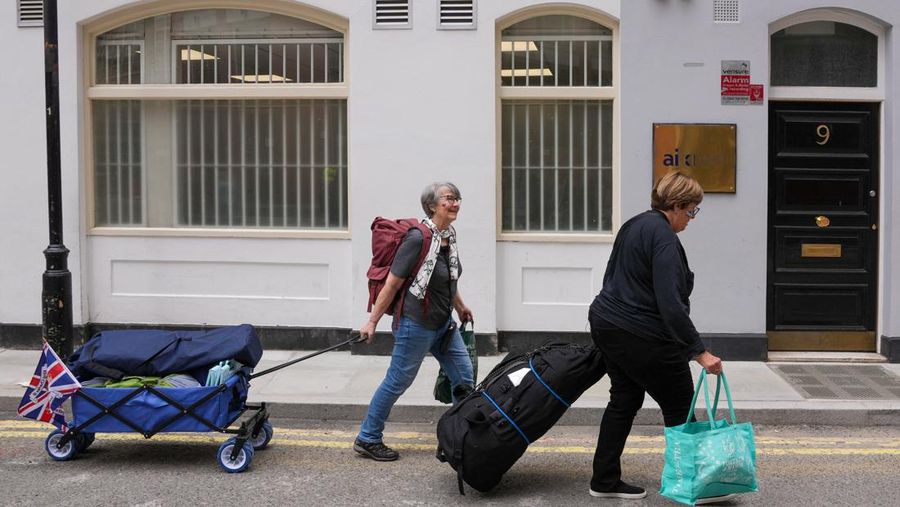Penggemar kerajaan Inggris, Mary-Jane Willows dari Inggris dan Donna Werner dari AS berjalan ke The Mall untuk mendirikan kemah jelang Penobatan Raja Charles, di London, Inggris, Selasa (2/5/2023). REUTERS/Maja Smiejkowska
