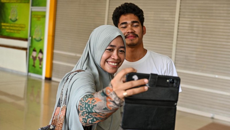 Seorang kerabat memeluk seorang pria (R), bagian dari sekelompok mahasiswa Indonesia yang dievakuasi dari Sudan yang dilanda konflik, setelah kedatangannya di Bandara Internasional Sultan Iskandar Muda di Blang Bintang, Provinsi Aceh pada 2 Mei 2023. - Sejak pertempuran pecah pada tanggal 15 April, beberapa pemerintah asing dari seluruh penjuru dunia telah mengorganisir konvoi jalan, pesawat terbang dan kapal untuk membawa ribuan warga negara mereka keluar dari Sudan, dan warga telah melarikan diri melalui darat ke negara tetangga. (CHAIDEER MAHYUDDIN/AFP via Getty Images)