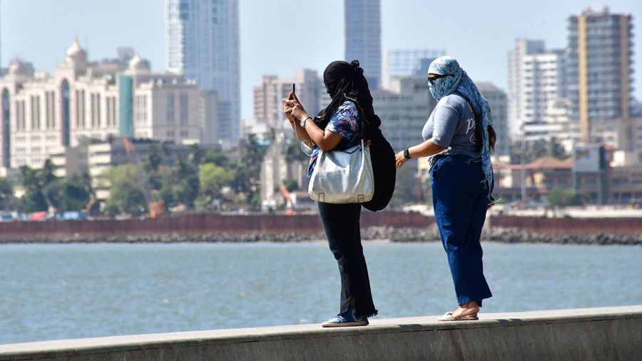 Warga menutupi diri mereka ntuk menghindari cuaca panas terik saat beraktivitas di Marine Drive, Mumbai, India, Selasa (2/5/2023). Bhushan Koyande/Hindustan Times via Getty Images