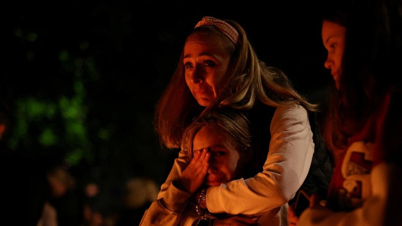 Seorang wanita mnaruh boneka saat menghadiri aksi menyalakan lilin dan tabur bunga pasca tragedi penembakan pada Sekolah Dasar di Kota Belgrade, Serbia, Rabu (3/5/2023) malam. (REUTERS/Antonio Bronic)