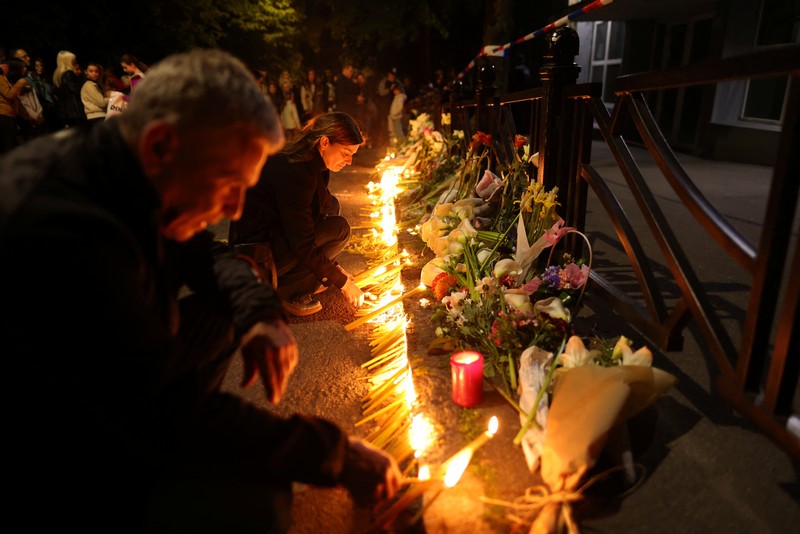 Seorang wanita mnaruh boneka saat menghadiri aksi menyalakan lilin dan tabur bunga pasca tragedi penembakan pada Sekolah Dasar di Kota Belgrade, Serbia, Rabu (3/5/2023) malam. (REUTERS/Antonio Bronic)