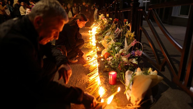 Seorang wanita mnaruh boneka saat menghadiri aksi menyalakan lilin dan tabur bunga pasca tragedi penembakan pada Sekolah Dasar di Kota Belgrade, Serbia, Rabu (3/5/2023) malam. (REUTERS/Antonio Bronic)