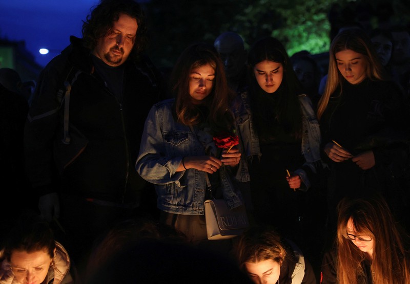 Seorang wanita mnaruh boneka saat menghadiri aksi menyalakan lilin dan tabur bunga pasca tragedi penembakan pada Sekolah Dasar di Kota Belgrade, Serbia, Rabu (3/5/2023) malam. (REUTERS/Antonio Bronic)