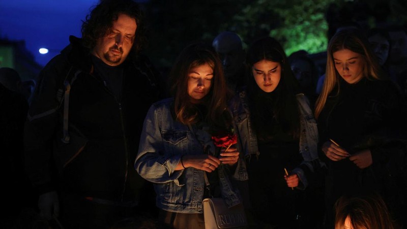 Seorang wanita mnaruh boneka saat menghadiri aksi menyalakan lilin dan tabur bunga pasca tragedi penembakan pada Sekolah Dasar di Kota Belgrade, Serbia, Rabu (3/5/2023) malam. (REUTERS/Antonio Bronic)