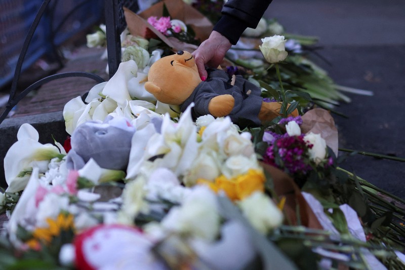 Seorang wanita mnaruh boneka saat menghadiri aksi menyalakan lilin dan tabur bunga pasca tragedi penembakan pada Sekolah Dasar di Kota Belgrade, Serbia, Rabu (3/5/2023) malam. (REUTERS/Antonio Bronic)