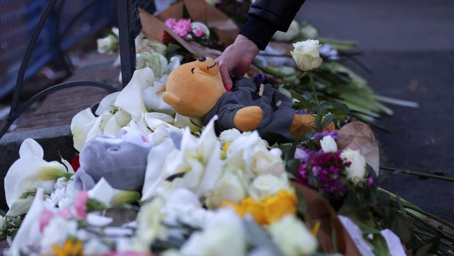 Seorang wanita mnaruh boneka saat menghadiri aksi menyalakan lilin dan tabur bunga pasca tragedi penembakan pada Sekolah Dasar di Kota Belgrade, Serbia, Rabu (3/5/2023) malam. (REUTERS/Antonio Bronic)