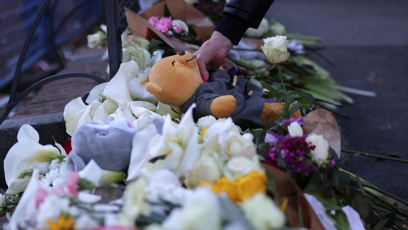 Seorang wanita mnaruh boneka saat menghadiri aksi menyalakan lilin dan tabur bunga pasca tragedi penembakan pada Sekolah Dasar di Kota Belgrade, Serbia, Rabu (3/5/2023) malam. (REUTERS/Antonio Bronic)