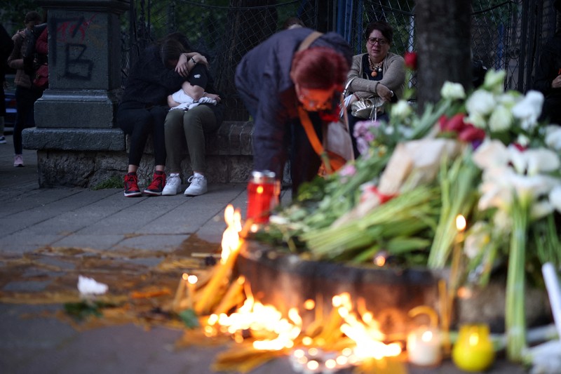 Seorang wanita mnaruh boneka saat menghadiri aksi menyalakan lilin dan tabur bunga pasca tragedi penembakan pada Sekolah Dasar di Kota Belgrade, Serbia, Rabu (3/5/2023) malam. (REUTERS/Antonio Bronic)