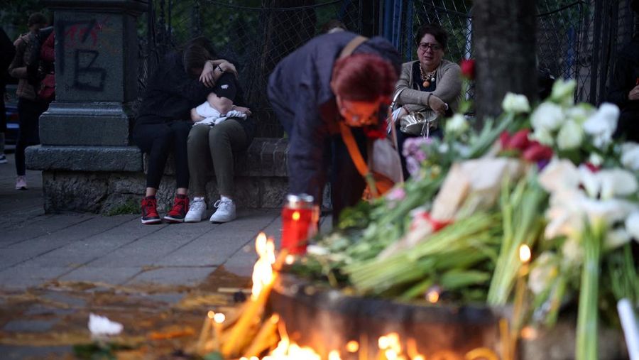 Seorang wanita mnaruh boneka saat menghadiri aksi menyalakan lilin dan tabur bunga pasca tragedi penembakan pada Sekolah Dasar di Kota Belgrade, Serbia, Rabu (3/5/2023) malam. (REUTERS/Antonio Bronic)