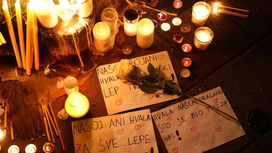 Seorang wanita mnaruh boneka saat menghadiri aksi menyalakan lilin dan tabur bunga pasca tragedi penembakan pada Sekolah Dasar di Kota Belgrade, Serbia, Rabu (3/5/2023) malam. (REUTERS/Antonio Bronic)