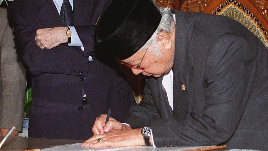 Foto arsip 15 Januari 1998 ini menunjukkan Presiden Indonesia saat itu Suharto menandatangani surat perjanjian baru di hadapan Direktur Jenderal Dana Moneter Internasional (IMF) Michel Camdessus di kediaman Suharto di Jakarta. Suharto menandatangani surat yang menguraikan reformasi besar-besaran dan langkah-langkah penghematan terkait dengan bailout besar-besaran yang dipimpin oleh IMF. Sepuluh tahun setelah memainkan peran kontroversial dalam krisis keuangan Asia, Dana Moneter Internasional (IMF) kini berada di tengah krisis identitasnya sendiri. Lembaga berusia enam dekade, yang meminjamkan lebih dari USD 38 miliar selama periode dua tahun ke negara-negara Asia dengan syarat mereka mengadopsi langkah-langkah penghematan yang ketat, mendapati dirinya 10 tahun kemudian dijauhi oleh banyak negara yang sebelumnya telah dibantu. (File Foto - AGUS LOLONG/AFP via Getty Images)