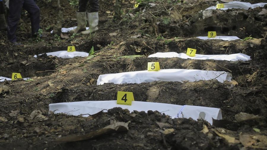 Petugas forensik memeriksa jenazah manusia pada lokasi penemujan kuburan massal di desa Ndoma, dekat Beni di Kivu Utara, Kongo, Sabtu (6/5/2023). (AP Photo)
