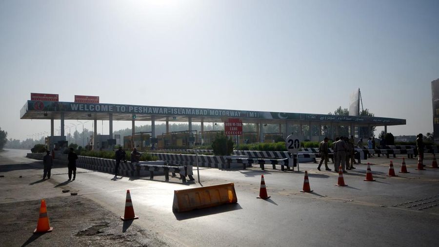 Seorang pria melintasi jalan melewati barikade yang dibakar oleh para pendukung mantan Perdana Menteri Pakistan Imran Khan selama protes terhadap penangkapannya, di Karachi, Pakistan, Selasa (9/5/2023). (REUTERS/AKHTAR SOOMRO)