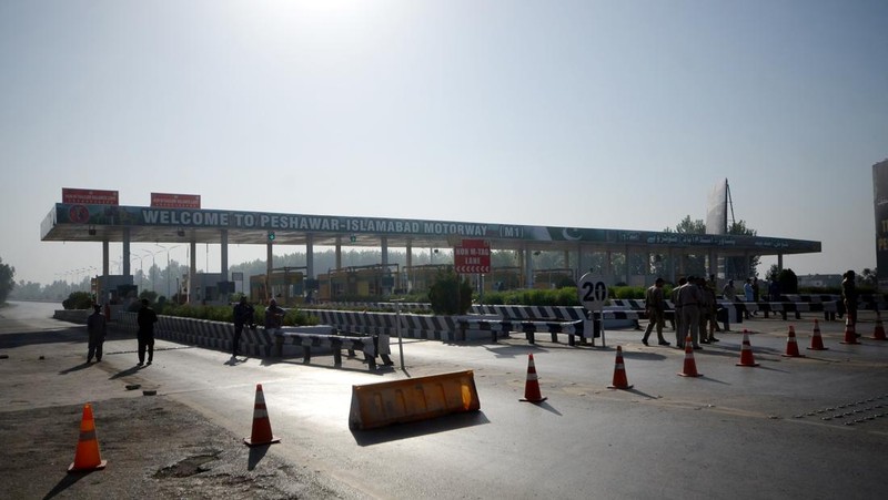 Seorang pria melintasi jalan melewati barikade yang dibakar oleh para pendukung mantan Perdana Menteri Pakistan Imran Khan selama protes terhadap penangkapannya, di Karachi, Pakistan, Selasa (9/5/2023). (REUTERS/AKHTAR SOOMRO)
