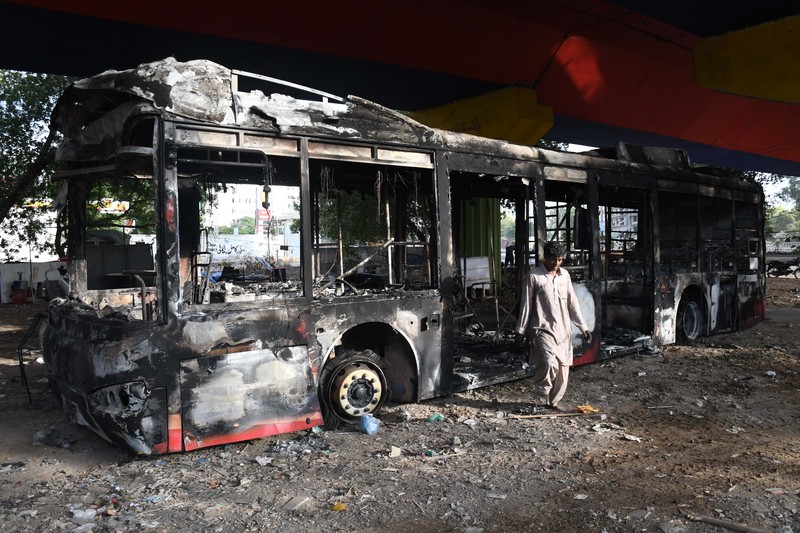 Seorang pria melintasi jalan melewati barikade yang dibakar oleh para pendukung mantan Perdana Menteri Pakistan Imran Khan selama protes terhadap penangkapannya, di Karachi, Pakistan, Selasa (9/5/2023). (REUTERS/AKHTAR SOOMRO)
