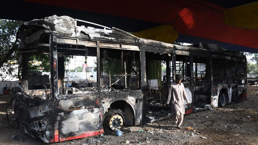 Seorang pria melintasi jalan melewati barikade yang dibakar oleh para pendukung mantan Perdana Menteri Pakistan Imran Khan selama protes terhadap penangkapannya, di Karachi, Pakistan, Selasa (9/5/2023). (REUTERS/AKHTAR SOOMRO)