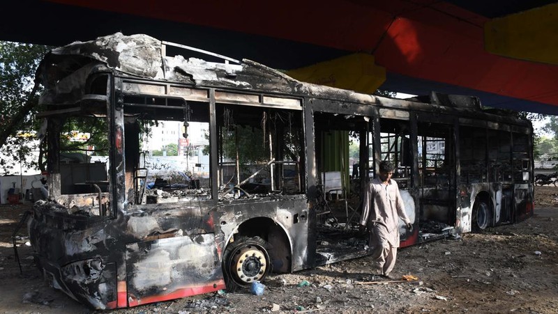 Seorang pria melintasi jalan melewati barikade yang dibakar oleh para pendukung mantan Perdana Menteri Pakistan Imran Khan selama protes terhadap penangkapannya, di Karachi, Pakistan, Selasa (9/5/2023). (REUTERS/AKHTAR SOOMRO)