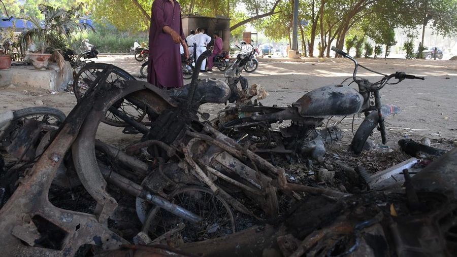 Seorang pria melintasi jalan melewati barikade yang dibakar oleh para pendukung mantan Perdana Menteri Pakistan Imran Khan selama protes terhadap penangkapannya, di Karachi, Pakistan, Selasa (9/5/2023). (REUTERS/AKHTAR SOOMRO)