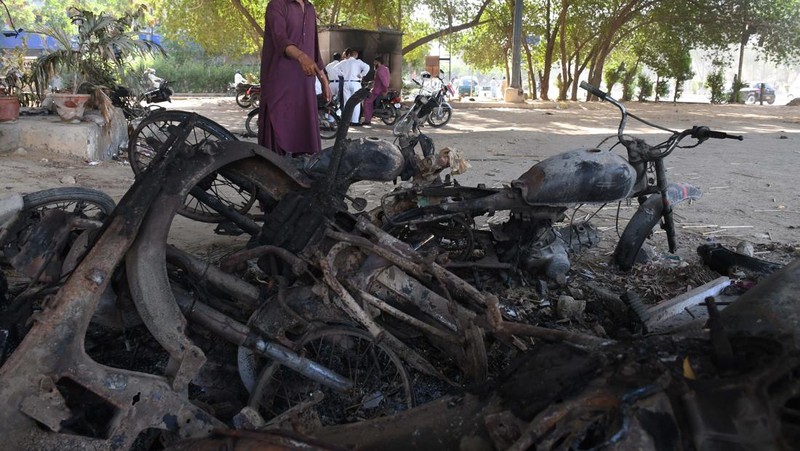 Seorang pria melintasi jalan melewati barikade yang dibakar oleh para pendukung mantan Perdana Menteri Pakistan Imran Khan selama protes terhadap penangkapannya, di Karachi, Pakistan, Selasa (9/5/2023). (REUTERS/AKHTAR SOOMRO)