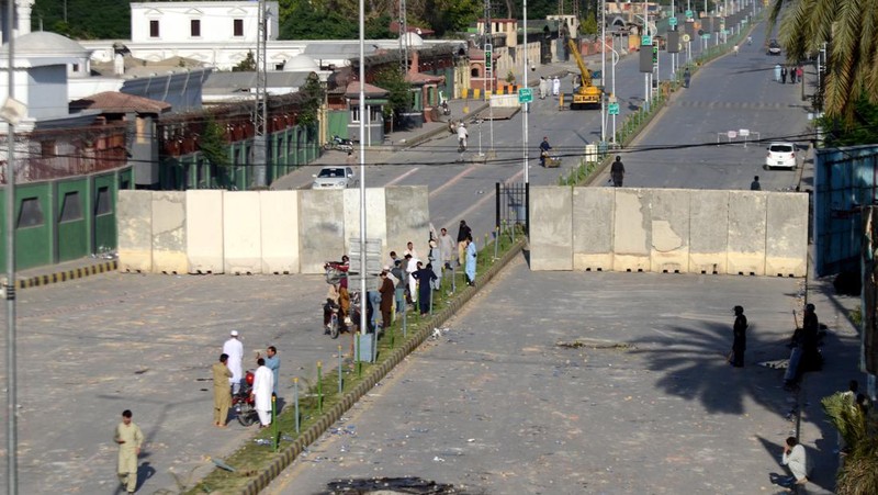 Seorang pria melintasi jalan melewati barikade yang dibakar oleh para pendukung mantan Perdana Menteri Pakistan Imran Khan selama protes terhadap penangkapannya, di Karachi, Pakistan, Selasa (9/5/2023). (REUTERS/AKHTAR SOOMRO)