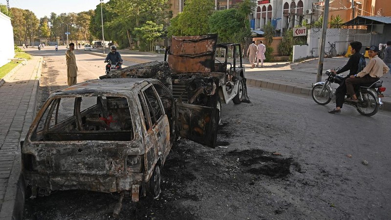 Seorang pria melintasi jalan melewati barikade yang dibakar oleh para pendukung mantan Perdana Menteri Pakistan Imran Khan selama protes terhadap penangkapannya, di Karachi, Pakistan, Selasa (9/5/2023). (REUTERS/AKHTAR SOOMRO)