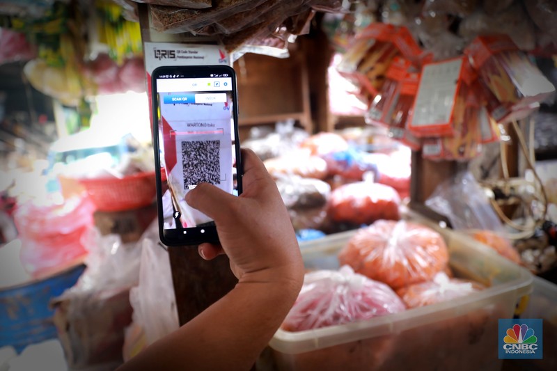 Seorang pedagang ikan asin menyiapkan dagangan dengan menyediakan sistem pembayaran Quick Response Code Indonesia Standard (QRIS) di Kawasan Pasar Tradisionan Pasar Minggu, Jakarta, Kamis, (11/5). Seorang pedagang ikan asin menyiapkan dagangan dengan menyediakan sistem pembayaran Quick Response Code Indonesia Standard (QRIS) di Kawasan Pasar Tradisionan Pasar Minggu, Jakarta, Kamis, (11/5). (CNBC Indonesia/Muhammad Sabki)