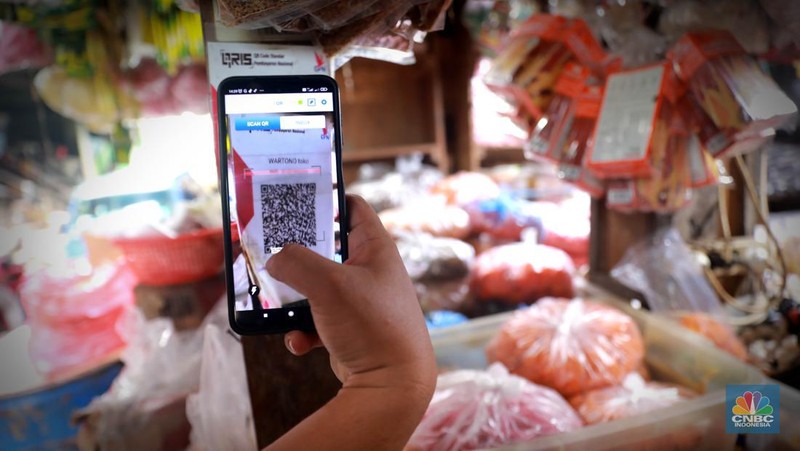 Seorang pedagang ikan asin menyiapkan dagangan dengan menyediakan sistem pembayaran Quick Response Code Indonesia Standard (QRIS) di Kawasan Pasar Tradisionan Pasar Minggu, Jakarta, Kamis, (11/5). (CNBC Indonesia/Muhammad Sabki)