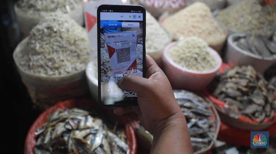Seorang pedagang ikan asin menyiapkan dagangan dengan menyediakan sistem pembayaran Quick Response Code Indonesia Standard (QRIS) di Kawasan Pasar Tradisionan Pasar Minggu, Jakarta, Kamis, (11/5). (վ/Muhammad Sabki)
