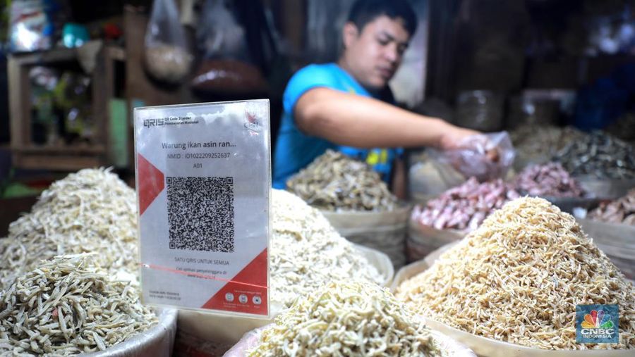 Seorang pedagang ikan asin menyiapkan dagangan dengan menyediakan sistem pembayaran Quick Response Code Indonesia Standard (QRIS) di Kawasan Pasar Tradisionan Pasar Minggu, Jakarta, Kamis, (11/5). (CNBC Indonesia/Muhammad Sabki)