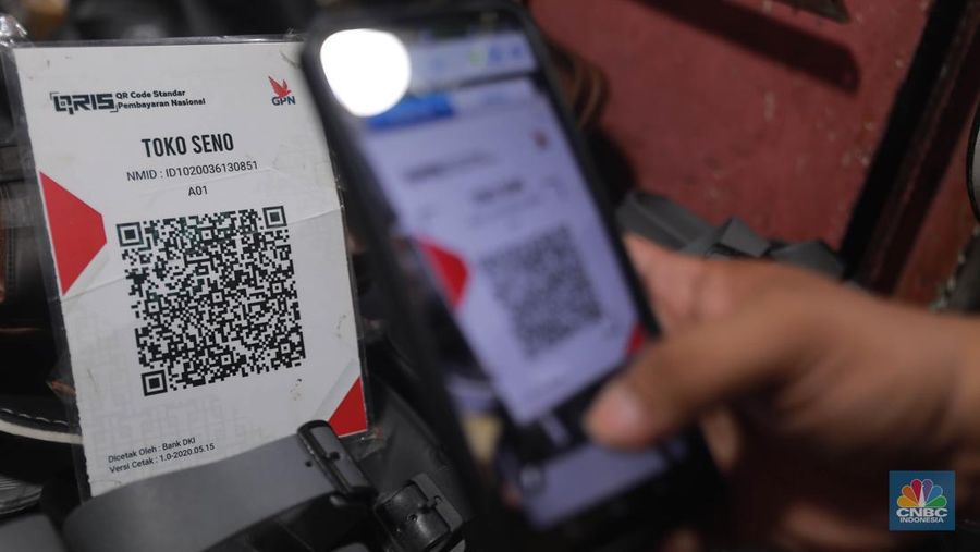 Seorang pedagang ikan asin menyiapkan dagangan dengan menyediakan sistem pembayaran Quick Response Code Indonesia Standard (QRIS) di Kawasan Pasar Tradisionan Pasar Minggu, Jakarta, Kamis, (11/5). (վ/Muhammad Sabki)