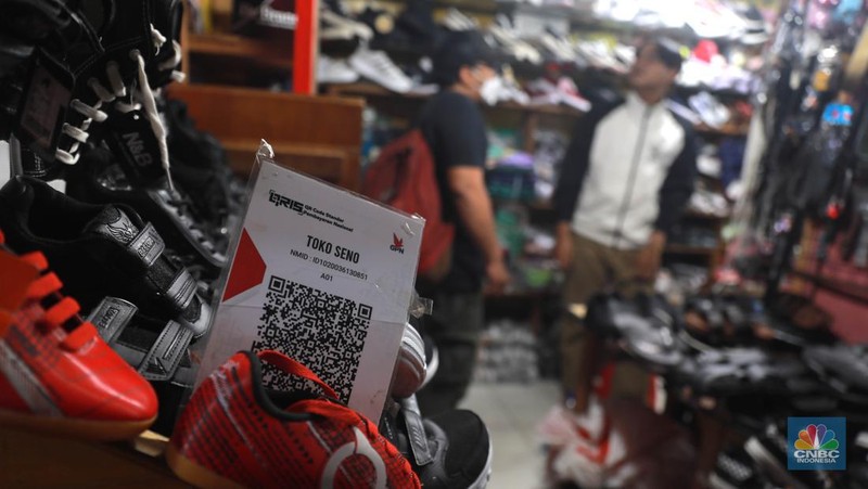 Seorang pedagang ikan asin menyiapkan dagangan dengan menyediakan sistem pembayaran Quick Response Code Indonesia Standard (QRIS) di Kawasan Pasar Tradisionan Pasar Minggu, Jakarta, Kamis, (11/5). (CNBC Indonesia/Muhammad Sabki)