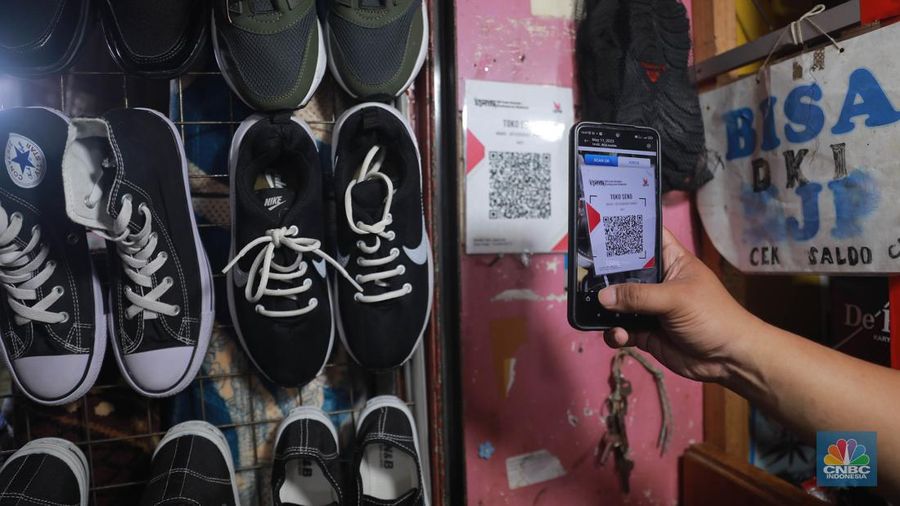 Seorang pedagang ikan asin menyiapkan dagangan dengan menyediakan sistem pembayaran Quick Response Code Indonesia Standard (QRIS) di Kawasan Pasar Tradisionan Pasar Minggu, Jakarta, Kamis, (11/5). (CNBC Indonesia/Muhammad Sabki)