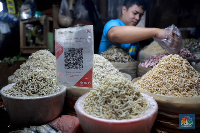 Seorang pedagang ikan asin menyiapkan dagangan dengan menyediakan sistem pembayaran Quick Response Code Indonesia Standard (QRIS) di Kawasan Pasar Tradisionan Pasar Minggu, Jakarta, Kamis, (11/5). Seorang pedagang ikan asin menyiapkan dagangan dengan menyediakan sistem pembayaran Quick Response Code Indonesia Standard (QRIS) di Kawasan Pasar Tradisionan Pasar Minggu, Jakarta, Kamis, (11/5). (CNBC Indonesia/Muhammad Sabki)