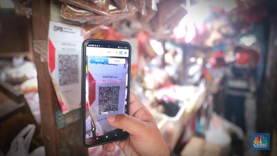 Seorang pedagang ikan asin menyiapkan dagangan dengan menyediakan sistem pembayaran Quick Response Code Indonesia Standard (QRIS) di Kawasan Pasar Tradisionan Pasar Minggu, Jakarta, Kamis, (11/5). (²©²ÊÍøÕ¾/Muhammad Sabki)