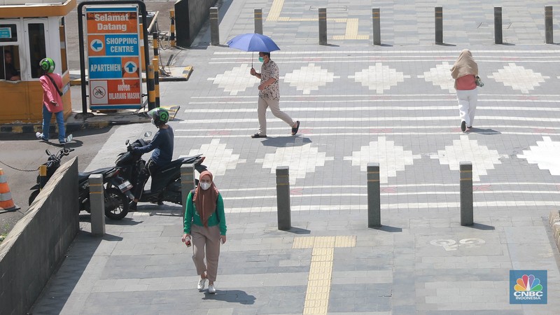 Sejumlah pekerja melintas di jalur pedestrian di kawasan Senayan Sudirman, Jakarta, Jumat (12/5/2023). (CNBC Indonesia/Muhammad Sabki)